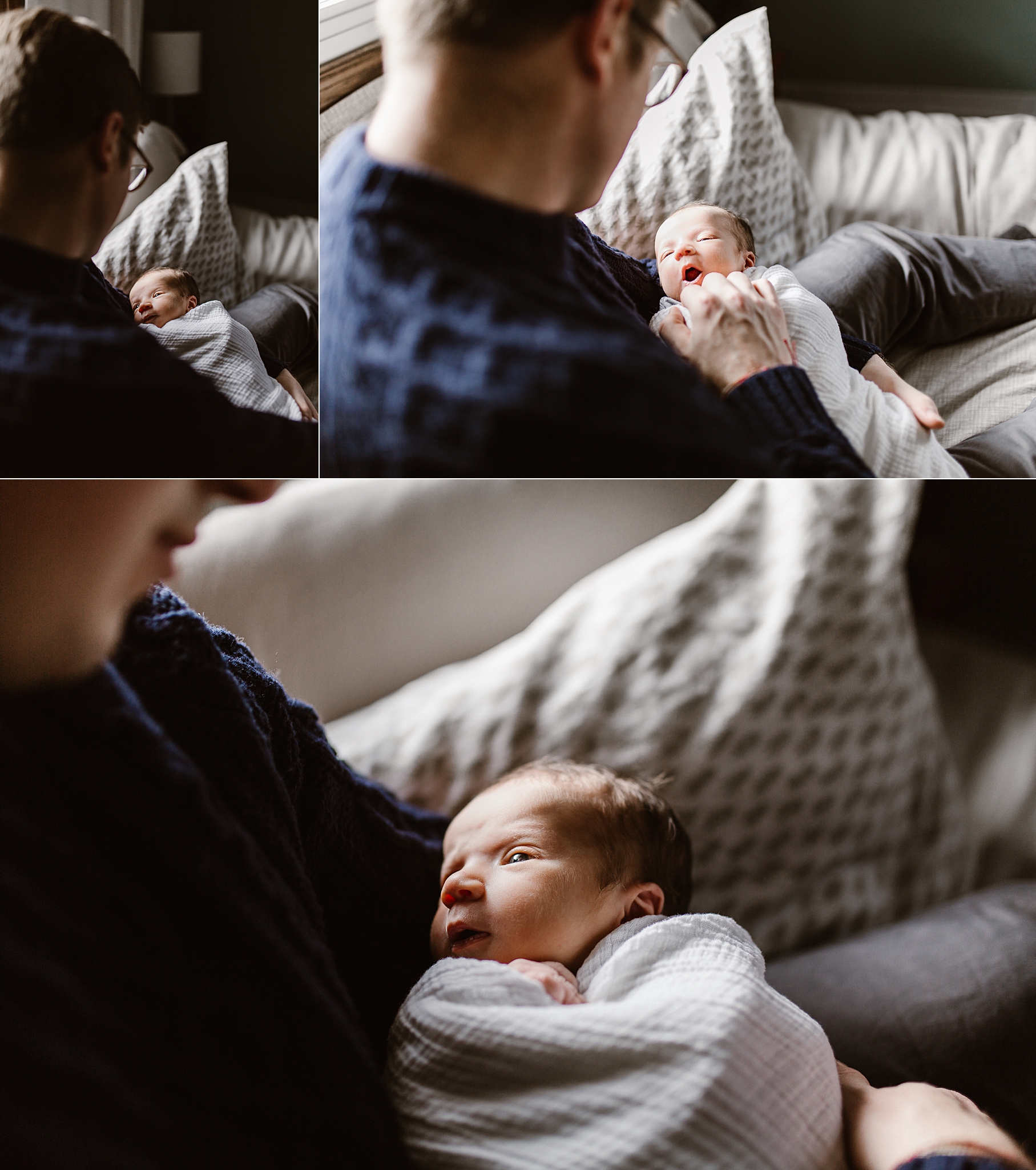 Father holding newborn baby girl as she yawns and looks up at him on a bed.