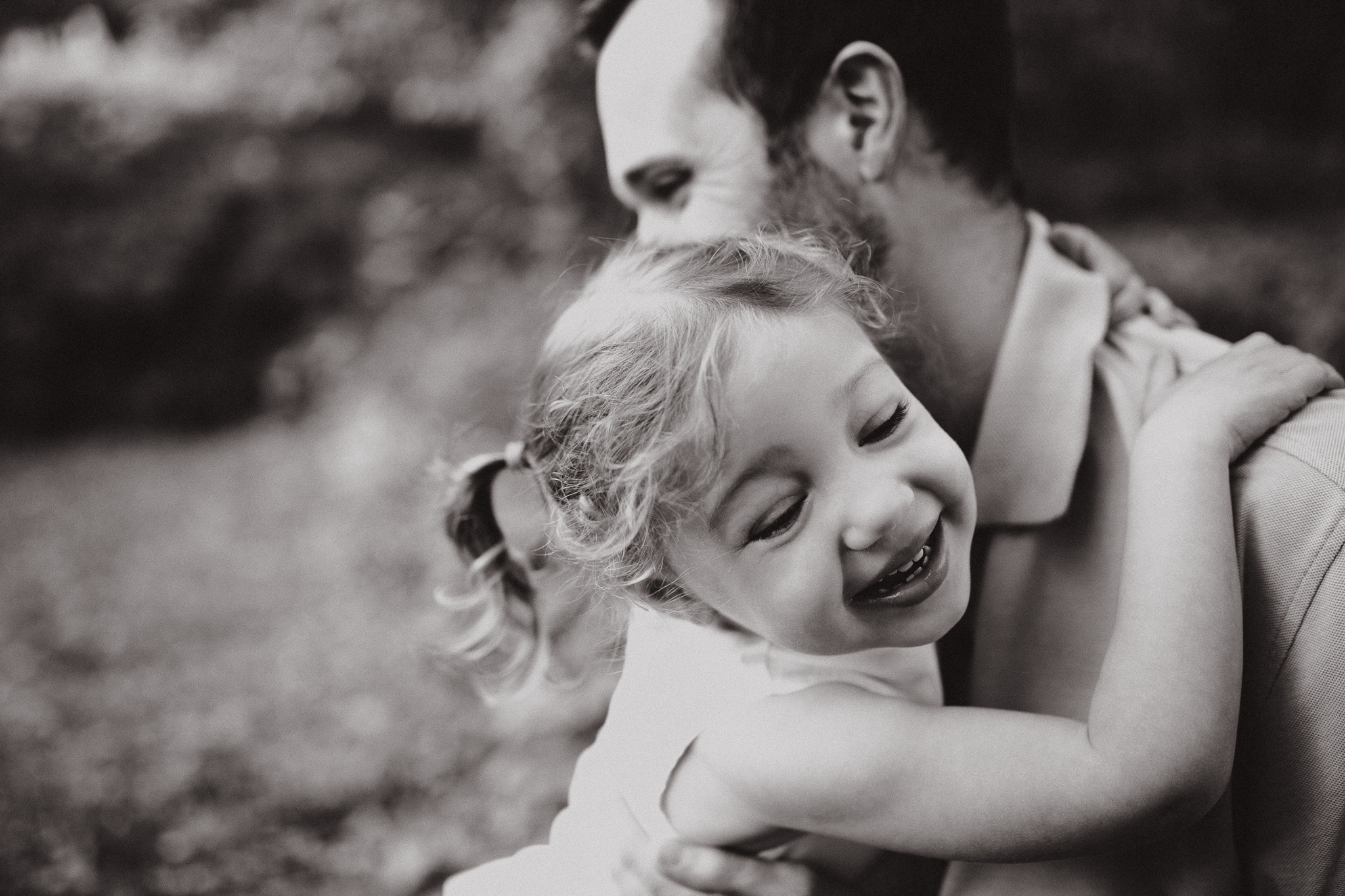 Laughing toddler girl with her arms wrapped around around her daddy.