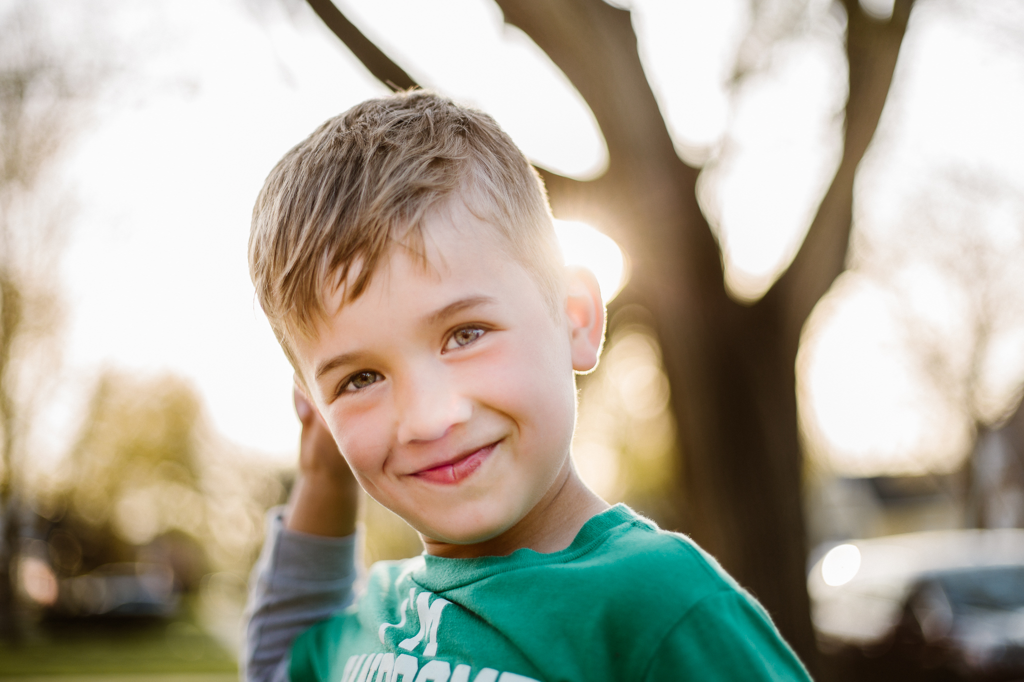 Young boy smiling with a sunset behind him.