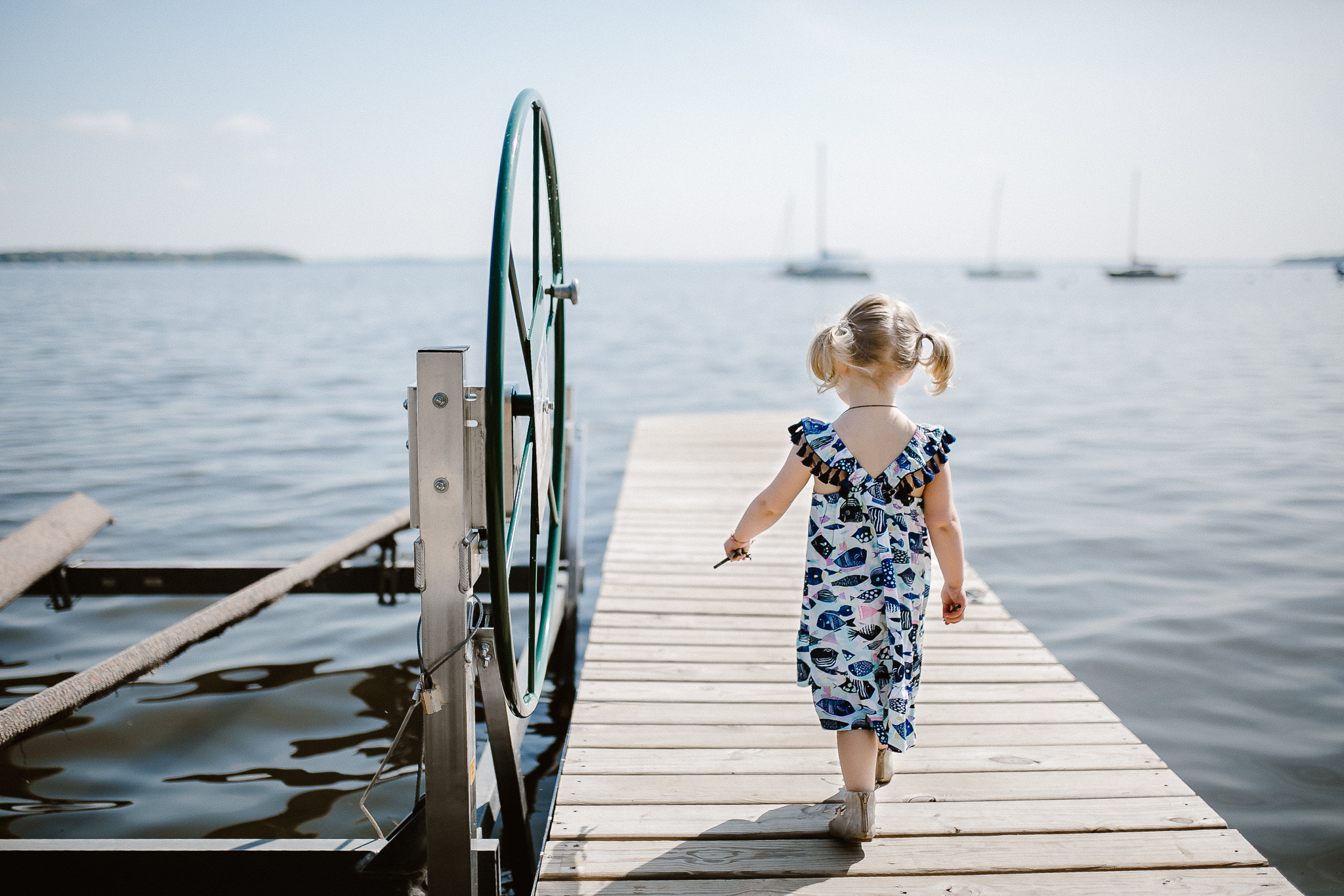 Toddler girl strutting down the dock in the water at the beach.