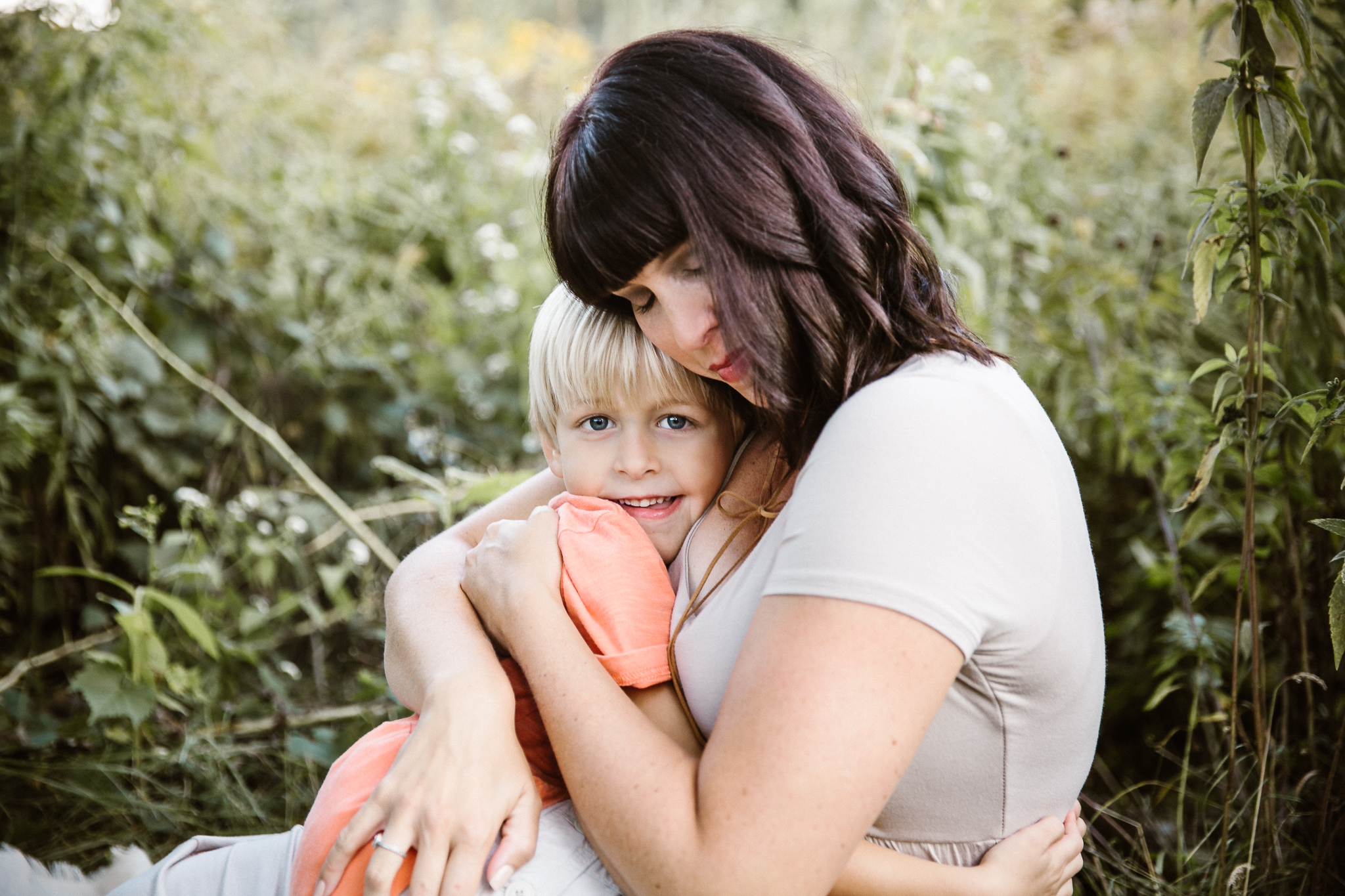 Mother tighly holding her toddler son with his arms wrapped around her.
