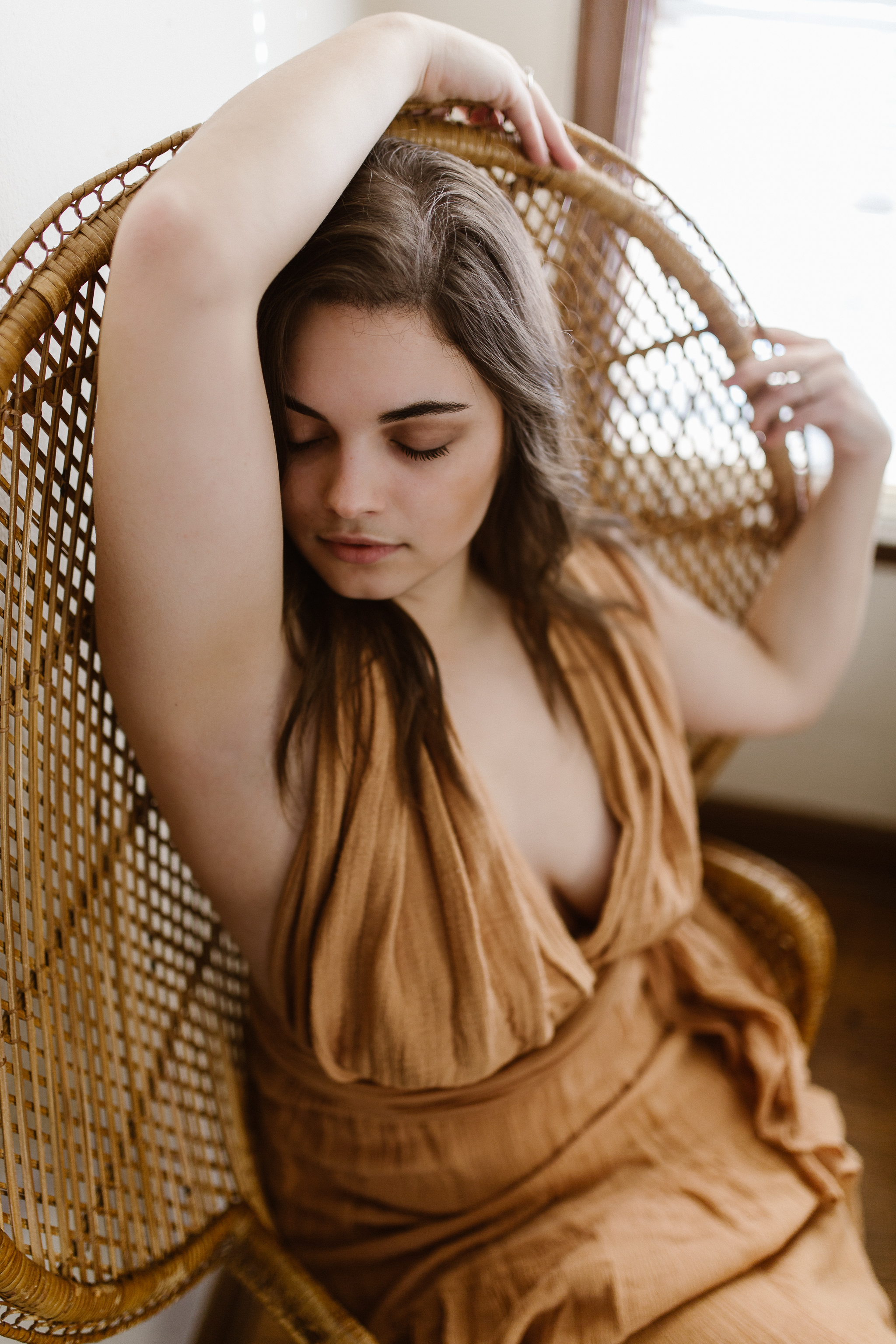 Intimate portrait of a woman in a flowing yellow dress in a wicker chair..